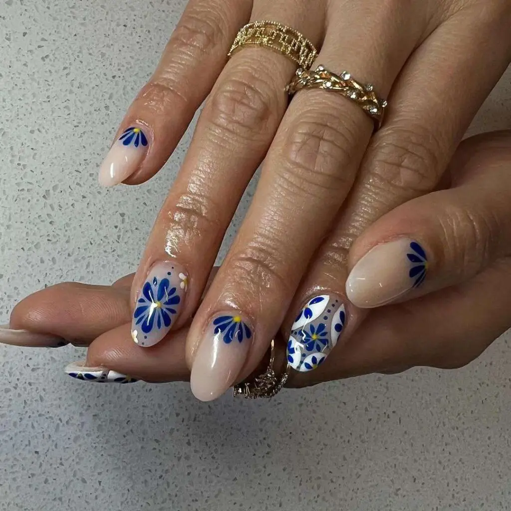 Nude almond nails with hand-painted blue and white daisy flowers