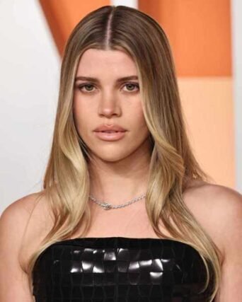 Center-parted bronde balayage hair styled with a diamond necklace