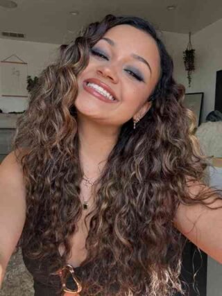 Curly brown hair with caramel highlights and smoky eye makeup in a selfie