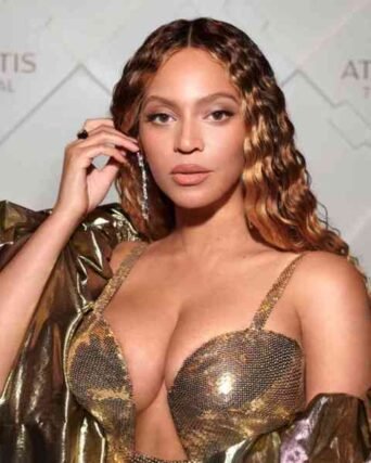 Dark curly hair with caramel highlights styled with a gold metallic dress