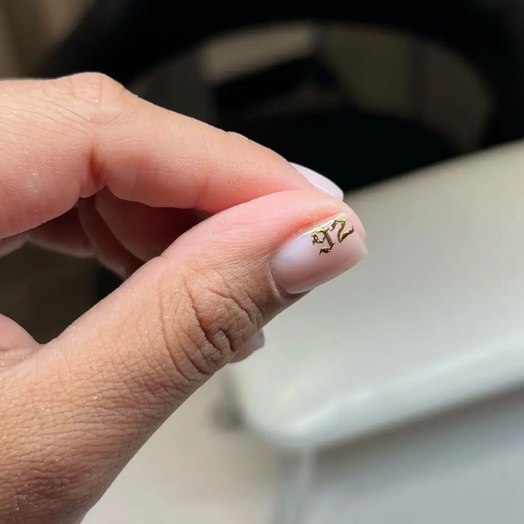 Nude nail with a small gold "92" foil number design