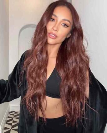 Long wavy auburn hair styled with a black cropped top and robe in a selfie