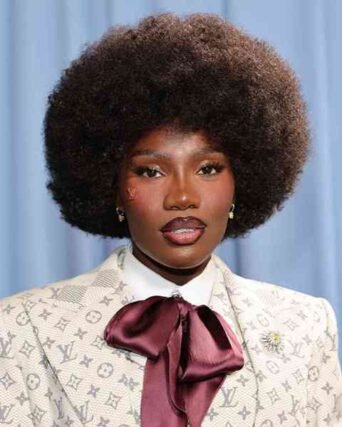 Natural afro hairstyle paired with a monogram print blazer and burgundy bow