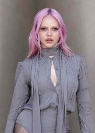Pastel pink hair paired with a grey pleated tie-neck blouse