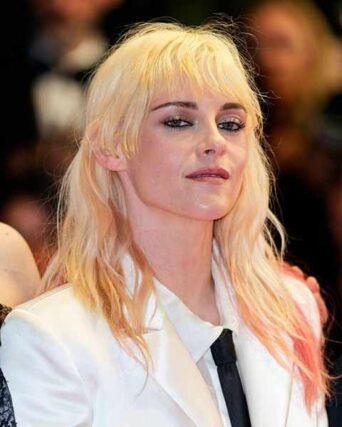 Platinum blonde shag haircut with bangs paired with a white blazer