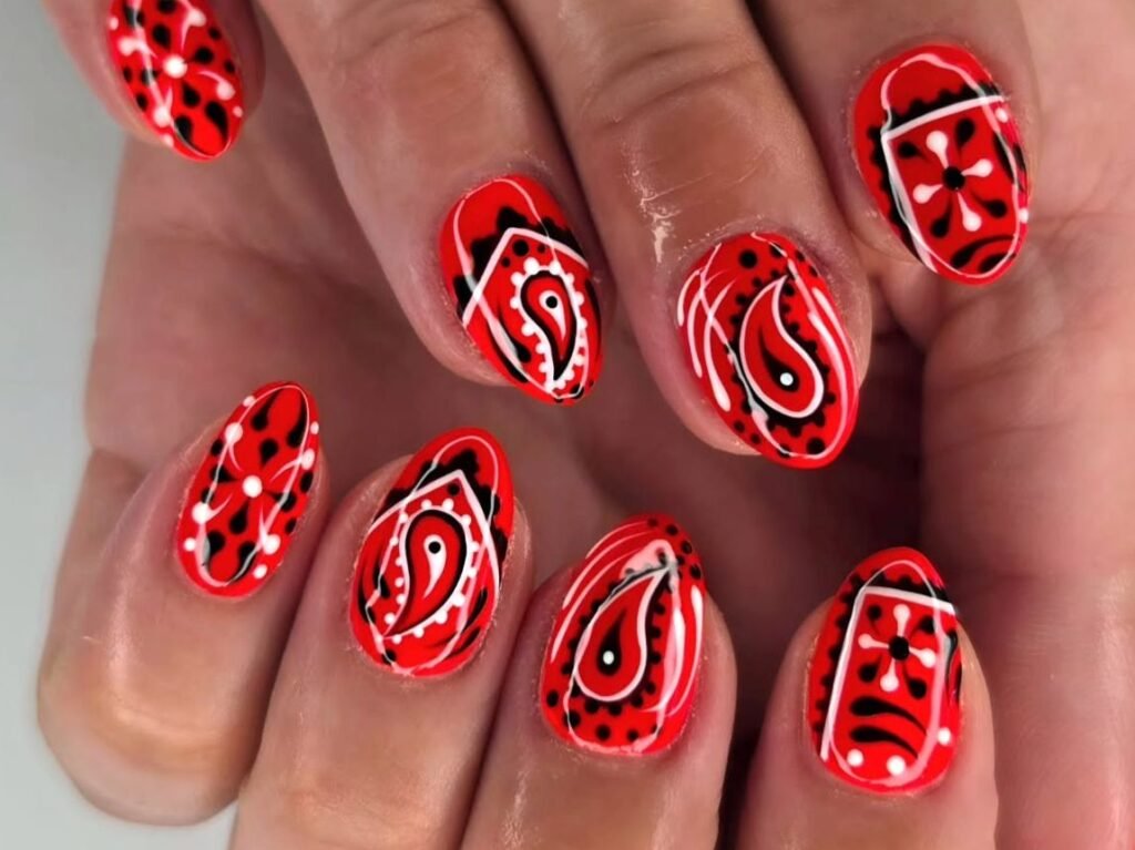 Red bandana-print nail art with black and white paisley patterns