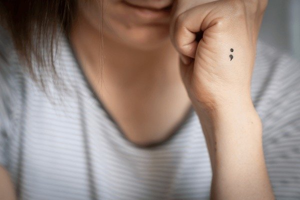Fine-line semicolon tattoo symbolizing mental health resilience