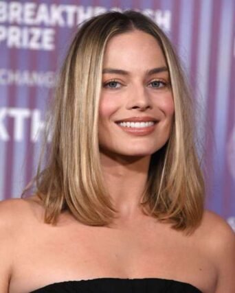 Straight blonde lob haircut paired with a black strapless top