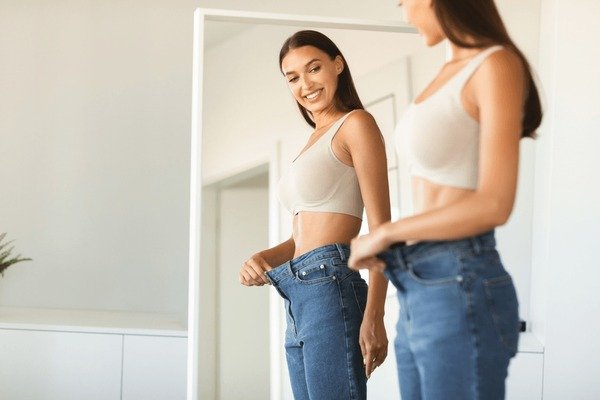 Woman checking trouser waistband fit in mirror
