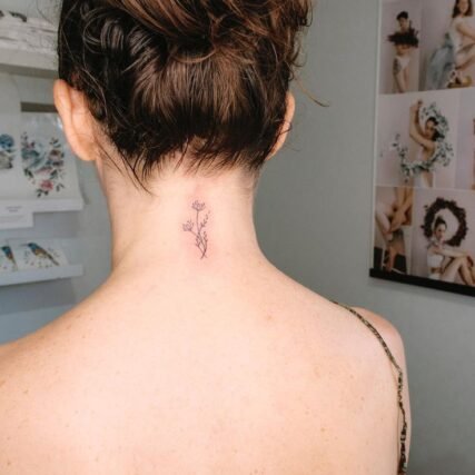 Small wildflower sprig tattoo on nape of neck for women