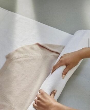 Wool sweater rolled inside a towel to soak up excess water